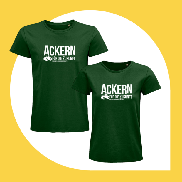 Flaschengrüne T-Shirts in geradem und tailliertem Schnitt mit weißem Text-und-Bild-Motiv: Ackern für die Zukunft – Wir haben Agrarindustrie satt. Neben dem Schriftzug ist auch ein moderner Traktor abgebildet.